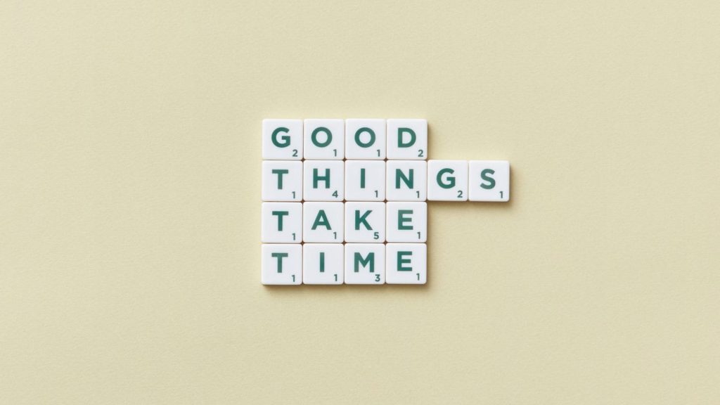 White tiles with green letters printed on them spell out the phrase "Good things take time."